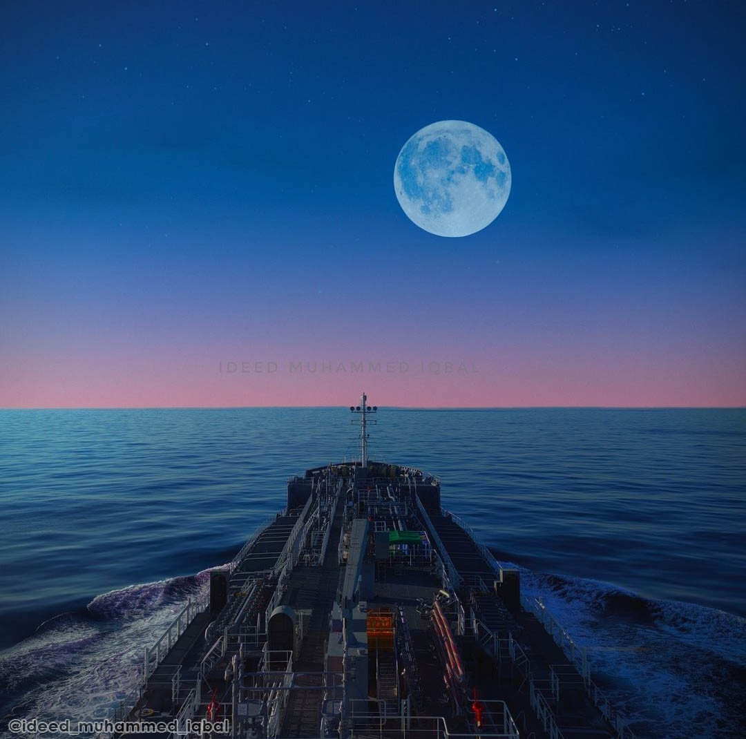 A tanker ship navigating on a calm ocean with the blue sky and a full moon ahead.