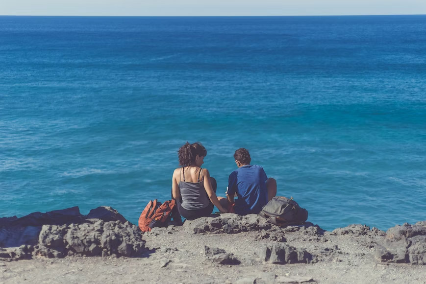 Two couples dating in front of the blue ocean.
