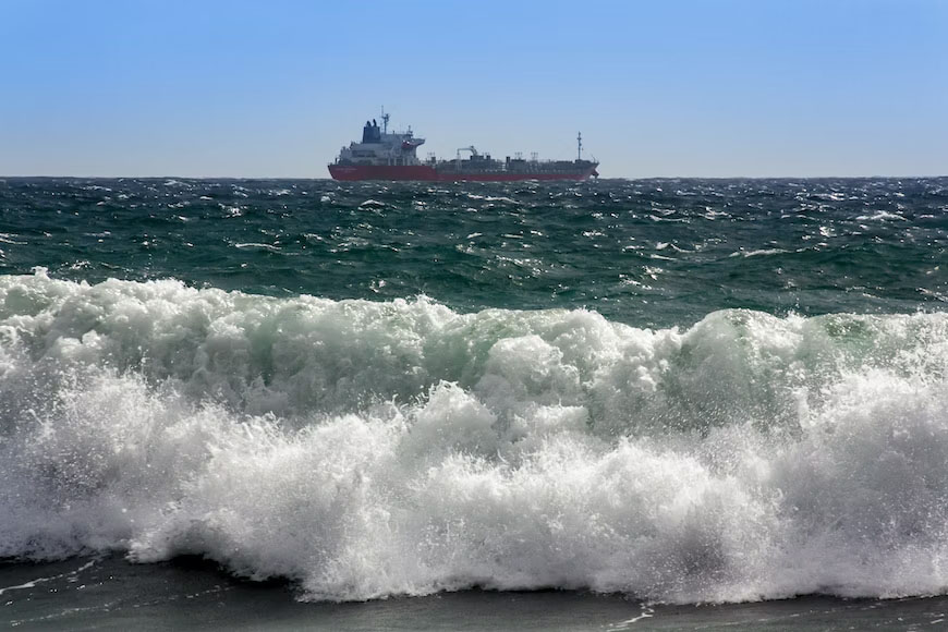 A tanker ship navigating in Gale 5 winds near the shore.