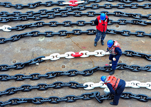 Shipyard crew inspecting the newly painted anchor chain.