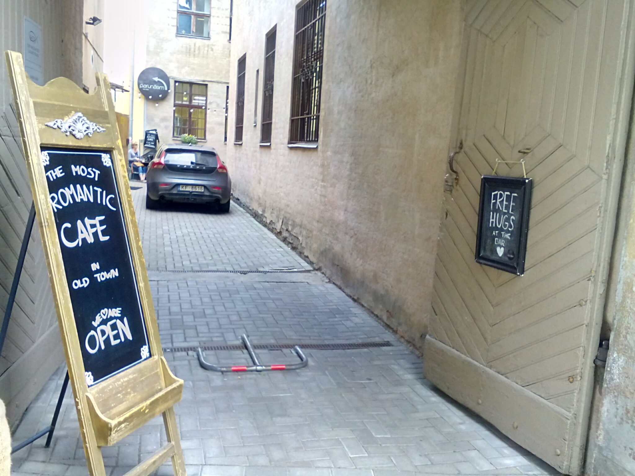 An alley in Riga, Latvia in the middle of the Old Town showing a sign indicating the most romantic cafe with free hugs.