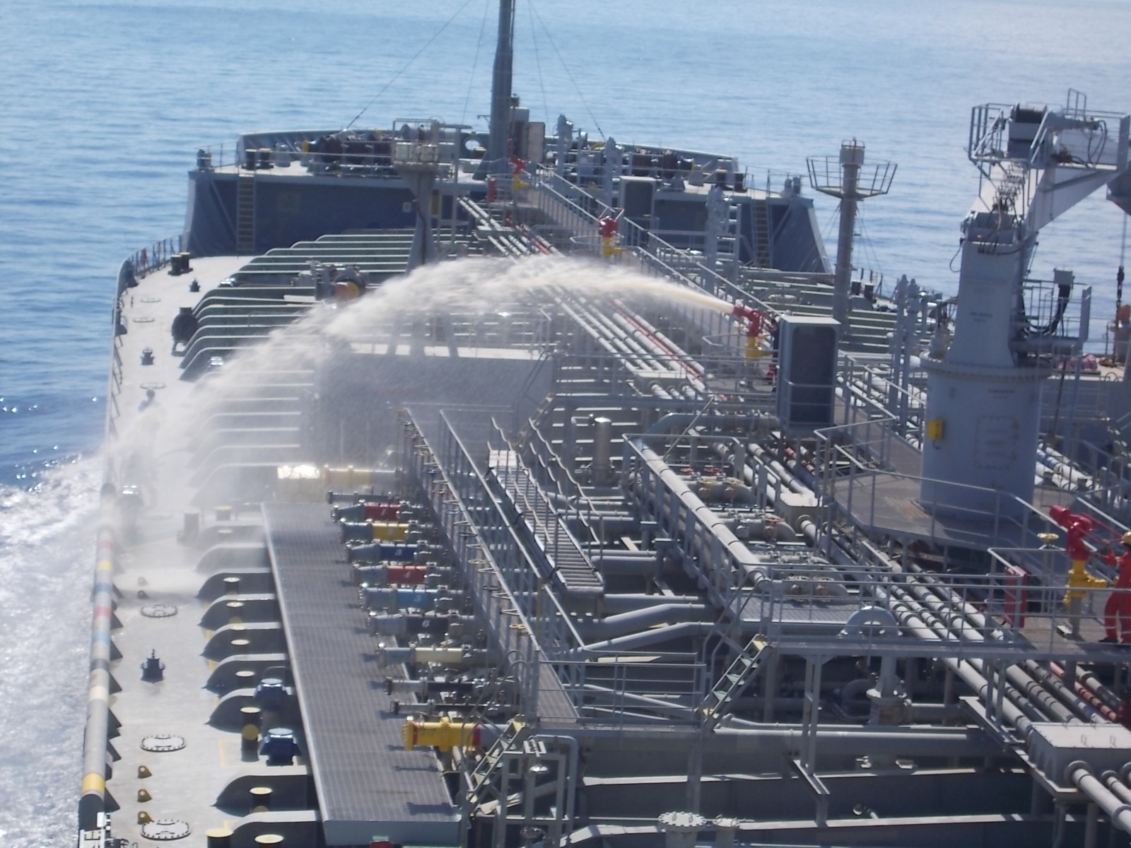 A tanker vessel opening her deck monitor where water is coming out as part of their fire drill.