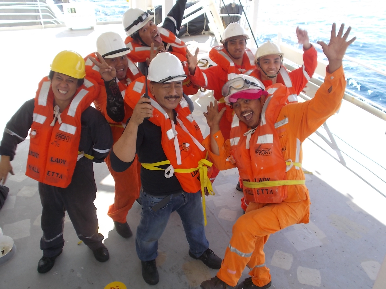 Seafarers wearing a lifejacket and making funny poses after a drill under the lifeboat.