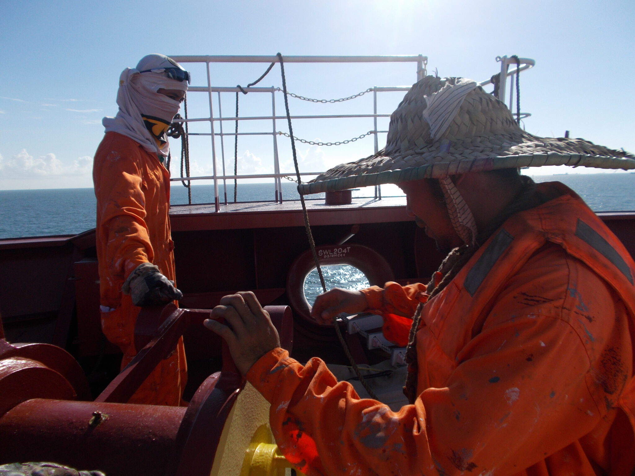 Deck crew preparing forward for working aloft on the ship's bulbous bow.