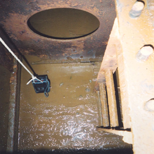 A gas detection equipment lowered with a rope inside a ballast tank.
