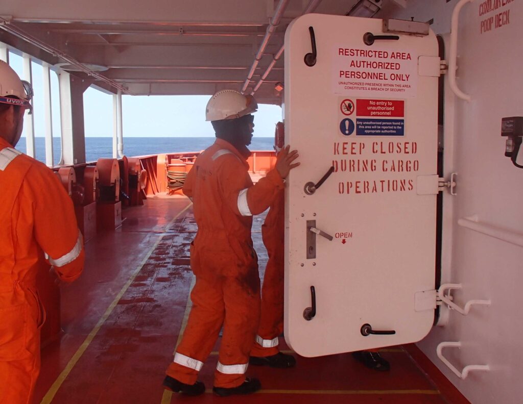 Crew entering the watertight door marked with "Restricted Area".