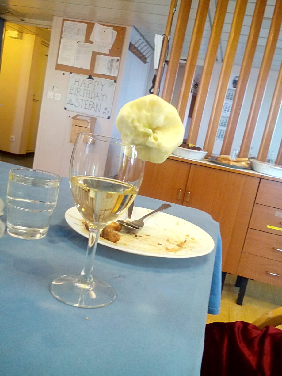 An empty plat and a wine with an apple on the side inside the mess hall.
