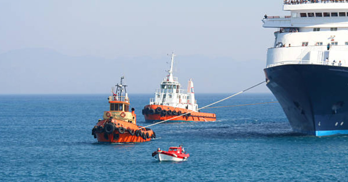 A tugboat towing a huge vessel using a tug's line while another tugboat escorting from behind.
