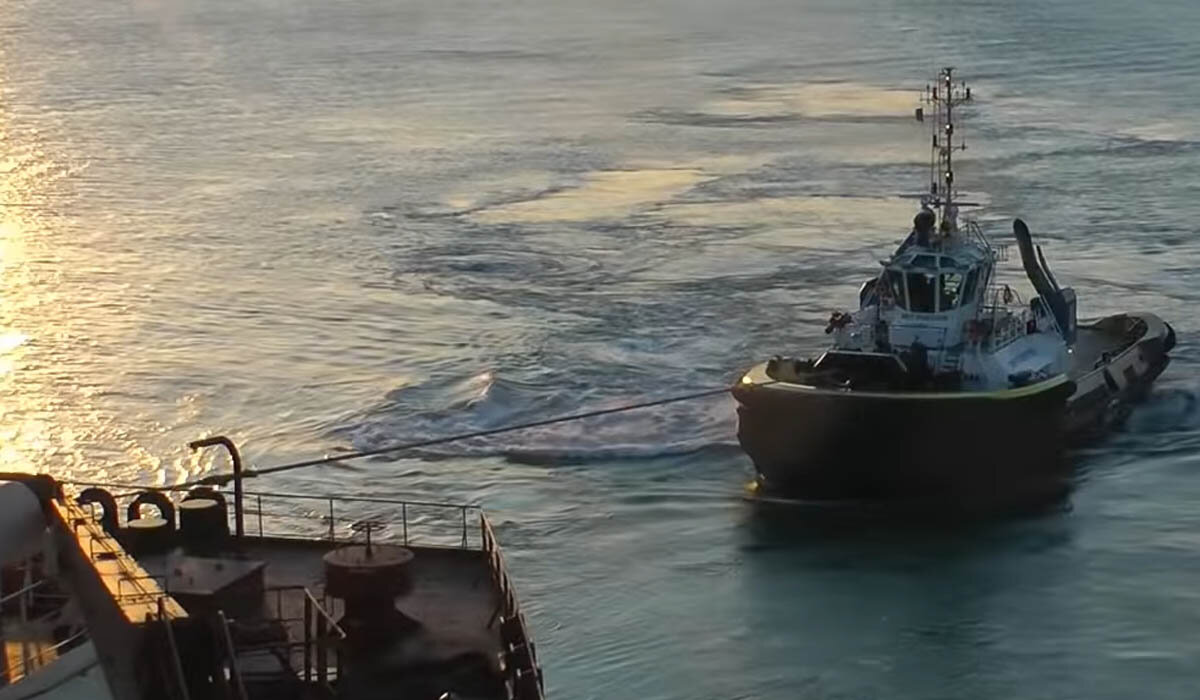 A tugboat pulling a ship while her line is made fast on the ship's stern. You can tell the tugboat's power in that image by looking at the line.