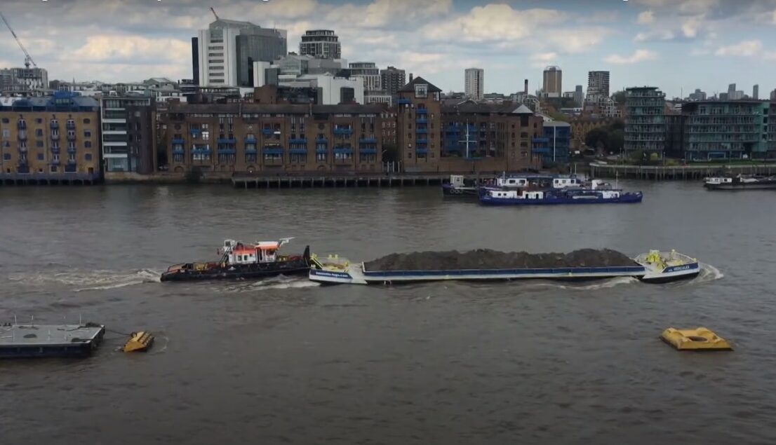 A harbor tug pushing a dumb barge across the River Thames.
