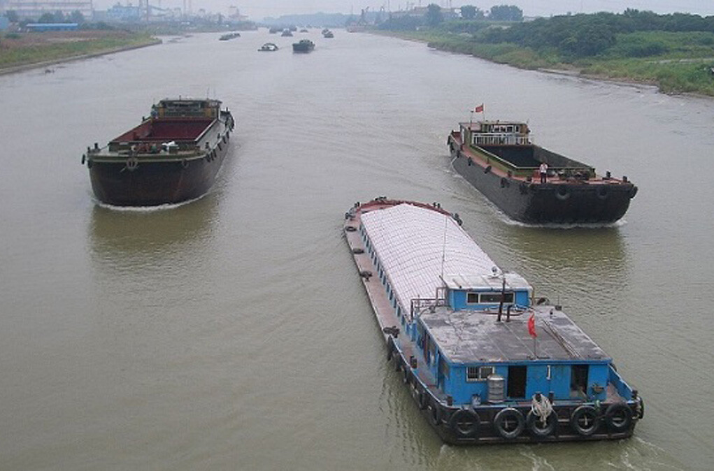 Barges of different sizes transporting various cargoes in a river.