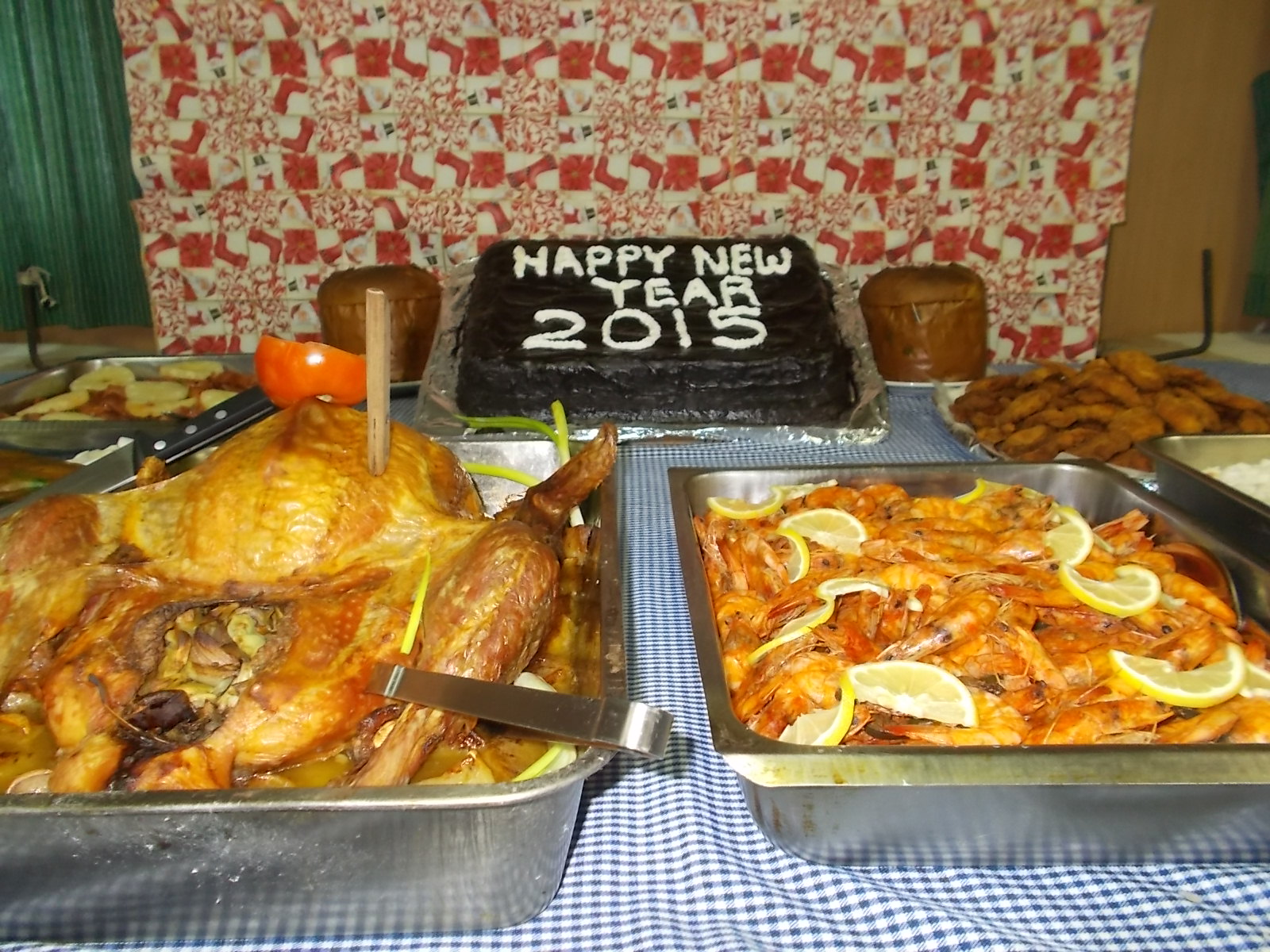 A chocolate cake written with "Happy New Year 2015" and other food served on the table inside the messroom.