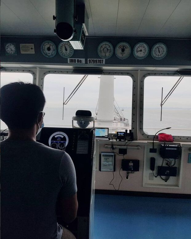 A helmsman wearing a facemask while steering a general cargo vessel.