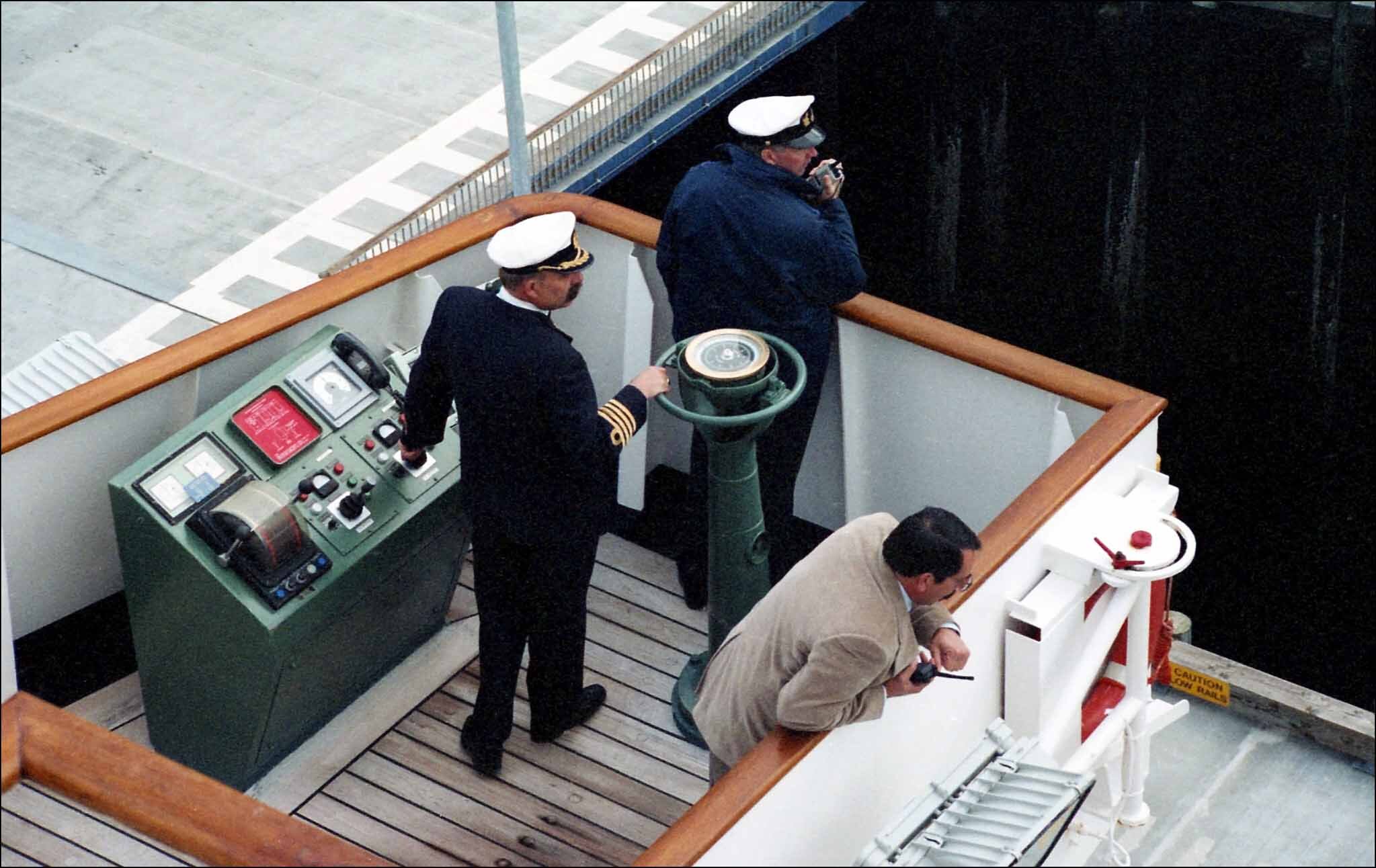 A ship captain, a pilot, and an OOW on the bridge wing during maneuvering