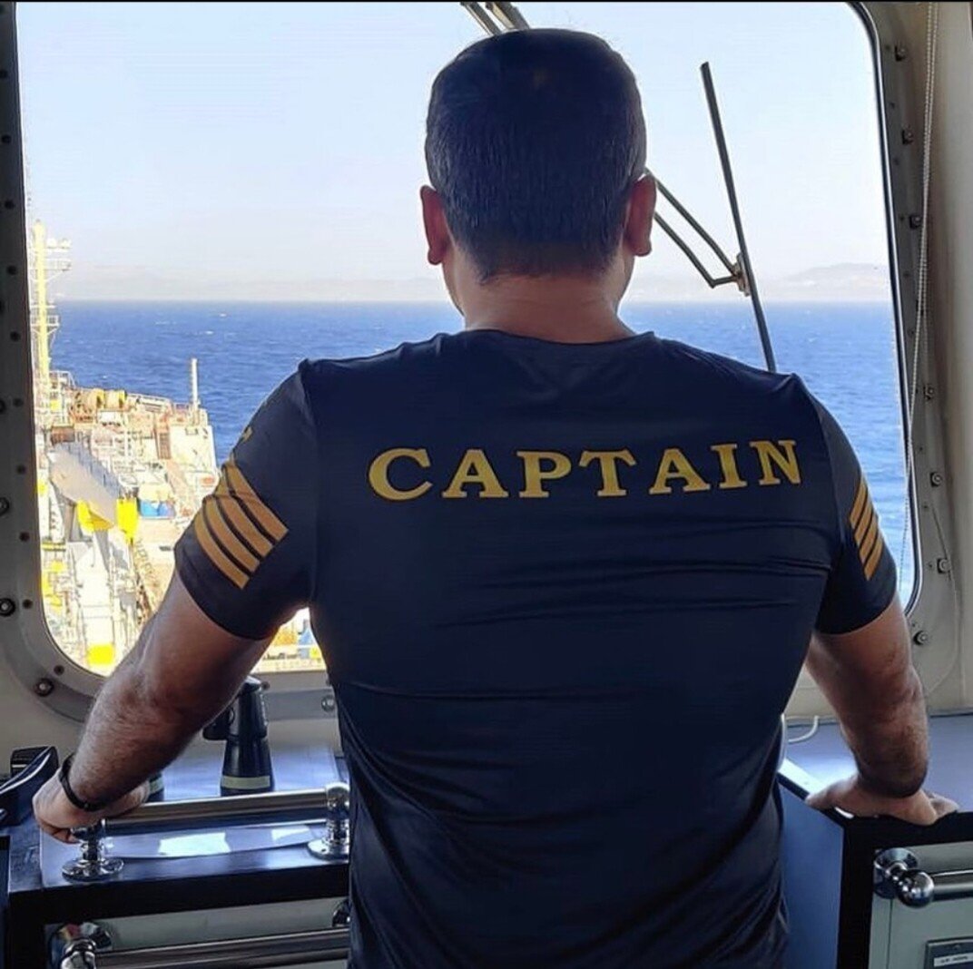 Captain on the bridge looking over the deck of the ship through the windshield.