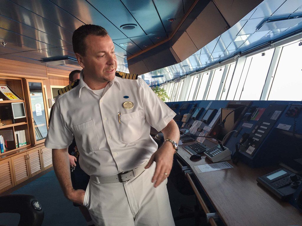A ship captain on the bridge looking at the various consoles, panels, and control equipment.