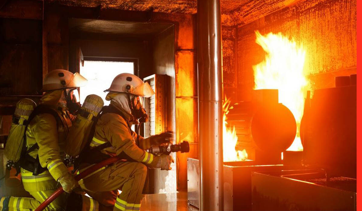 Two fire fighters extinguishing a fire in a compartment during advanced fire fighting course