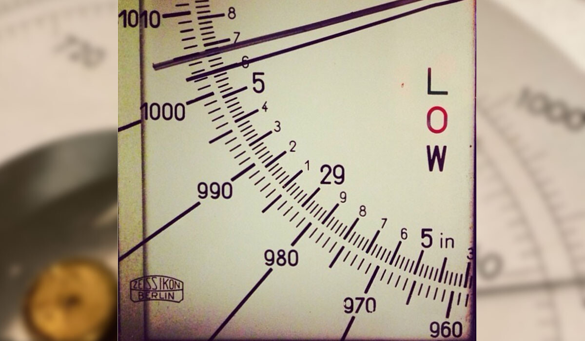An aneroid barometer reading 1002 mmHg which is nearing the low-pressure level.