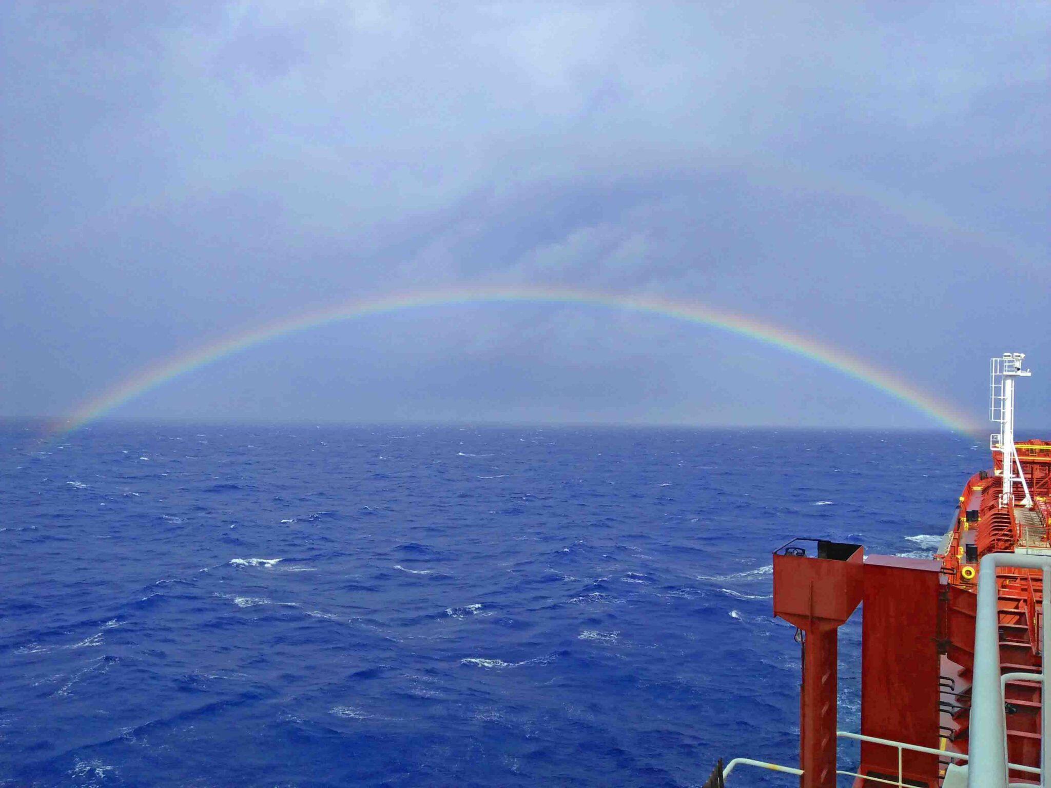 Rainbow forming over the horizon on the port bow of a tanker vessel.