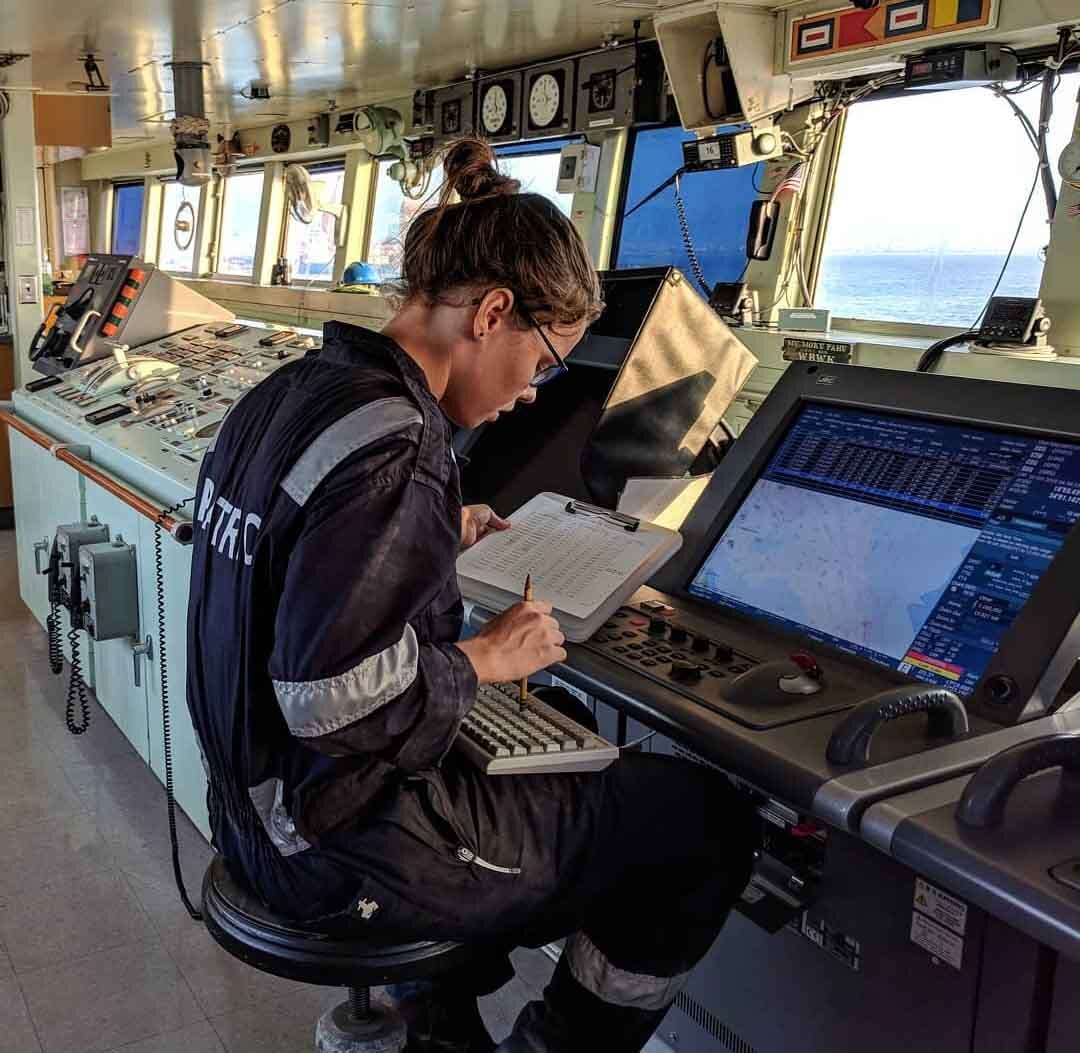 Second Officer @madeleineannawolczko holding a paper while sitting down in front of the ECDIS to prepare for the ship's voyage plan six hours before the intended departure.