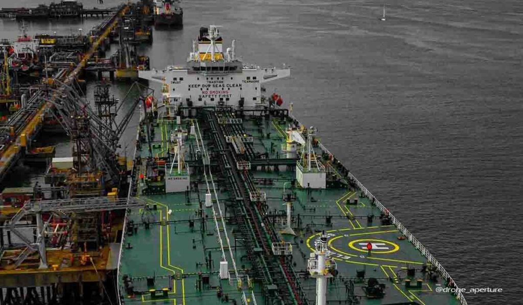 A tanker ship performing loading operation in port. where the shore gangway is positioned and the loading arm is connected.