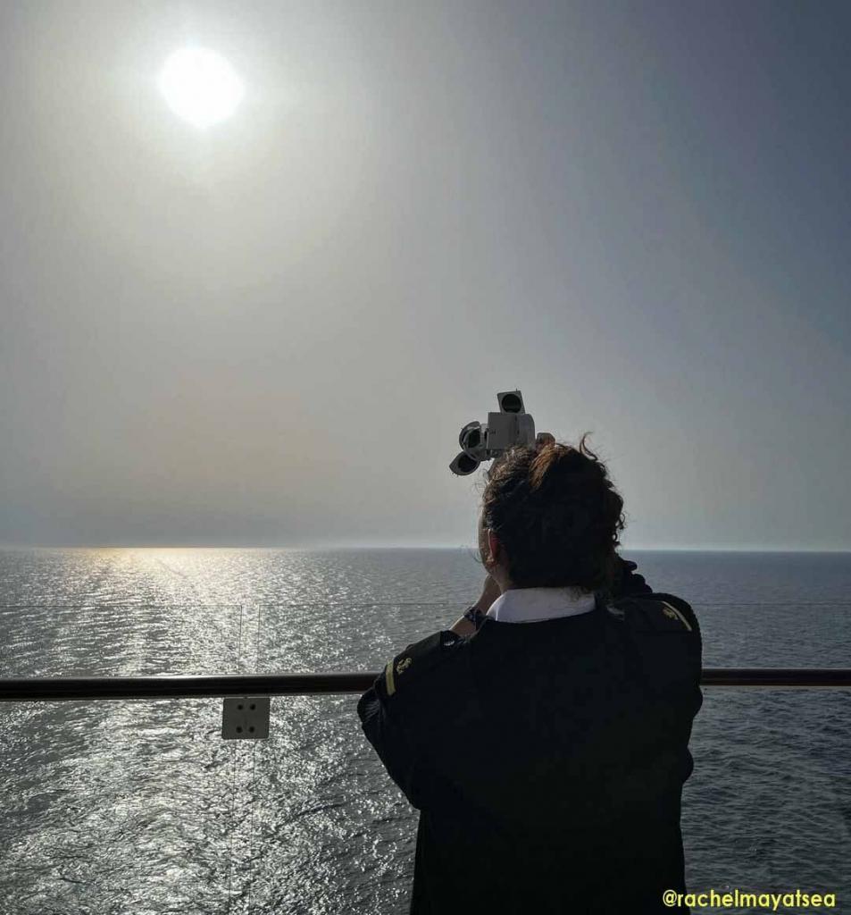 A seawoman taking the altitude of the sun using a sextant behind the vessel. This is oldest method of position fixing in marine navigation.