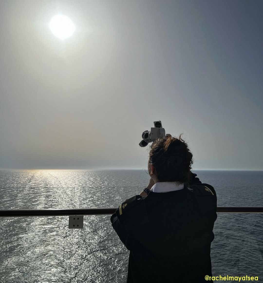 A seawoman taking the altitude of the sun using a sextant to find her position in the middle of the ocean.