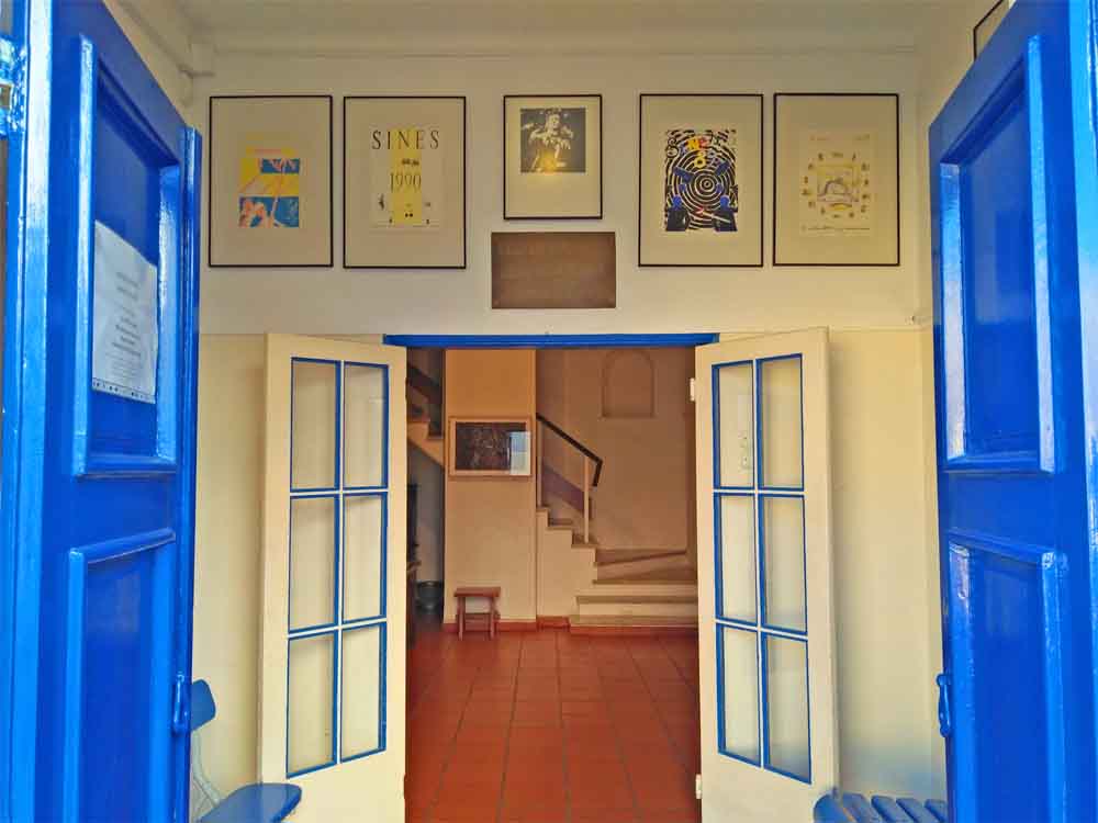 A blue and white doorway with posters on the walls leads into a room.