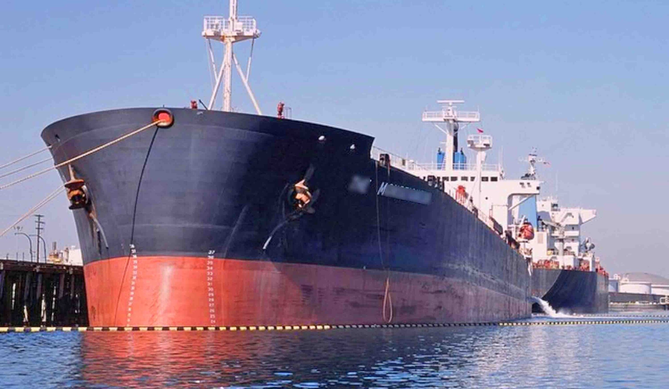 A tanker ship docked in a port with her fire wire lowered on the off-shore side of about 1 meter above the water level.