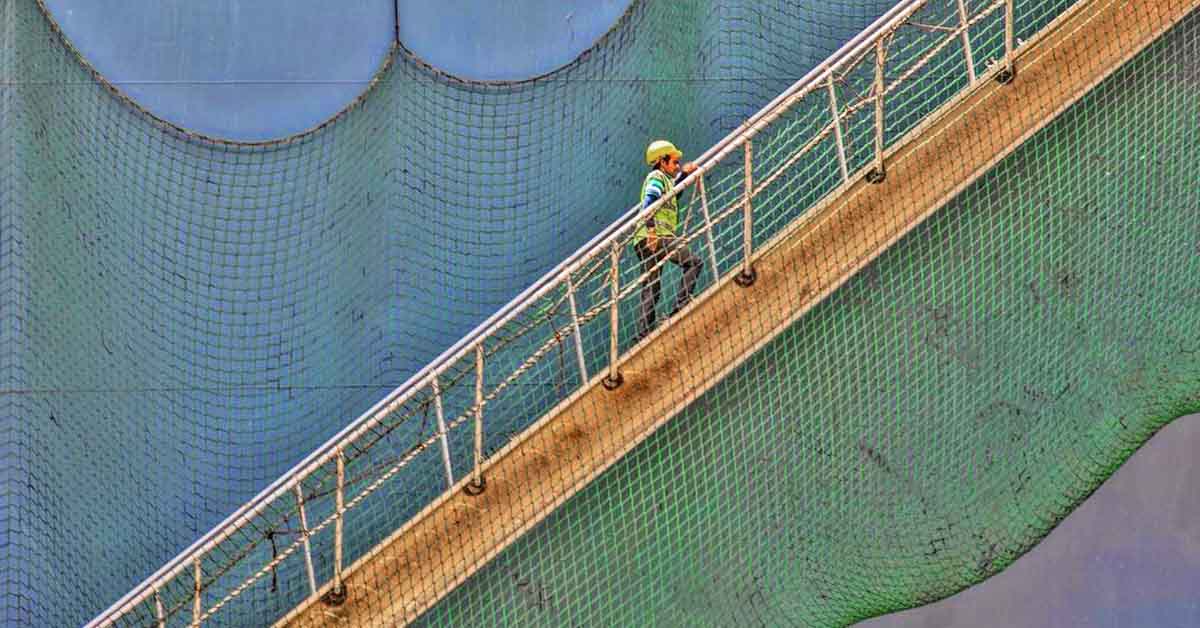 A Stevedore climbing the ship's accommodation ladder with safety net around it.