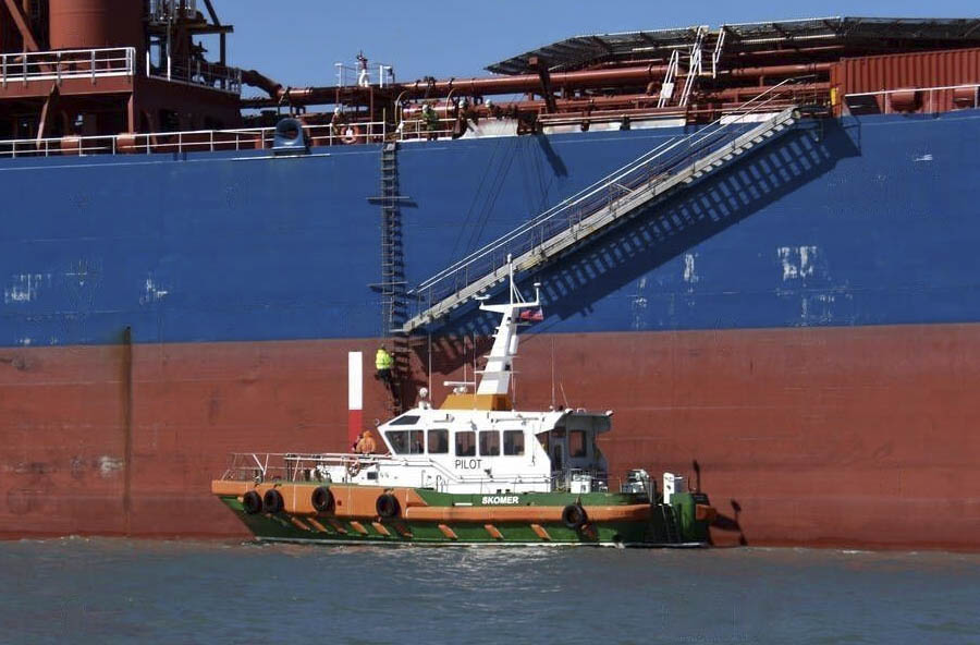 A pilot boat going alongside a ship so the pilot can climbed up the combination ladder safely