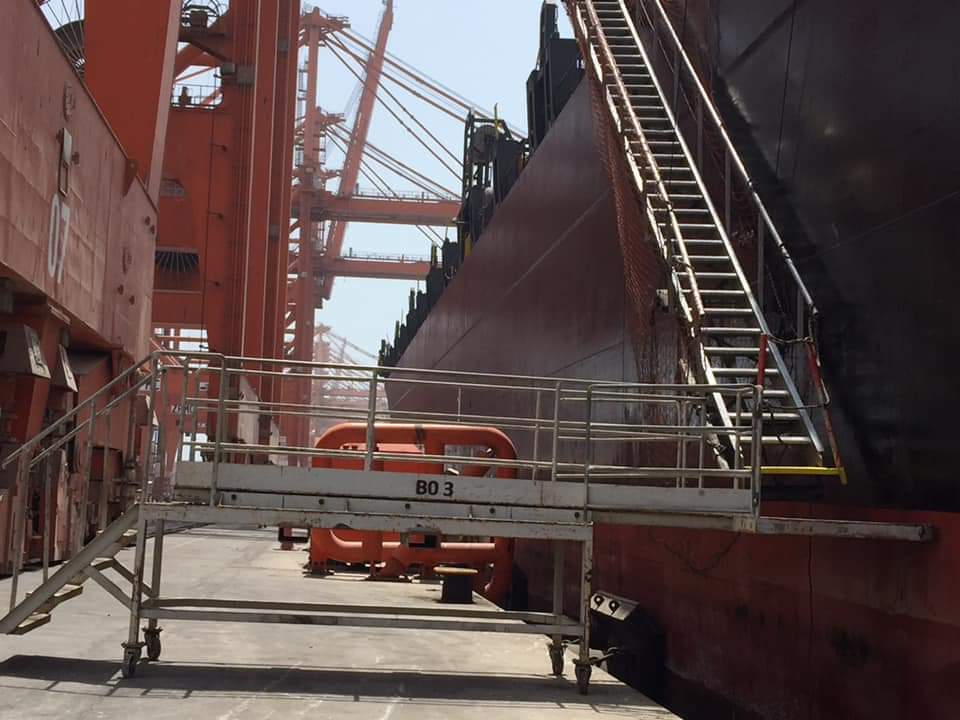 A ship's accommodation ladder used in tandem with the shore's portable gangway.