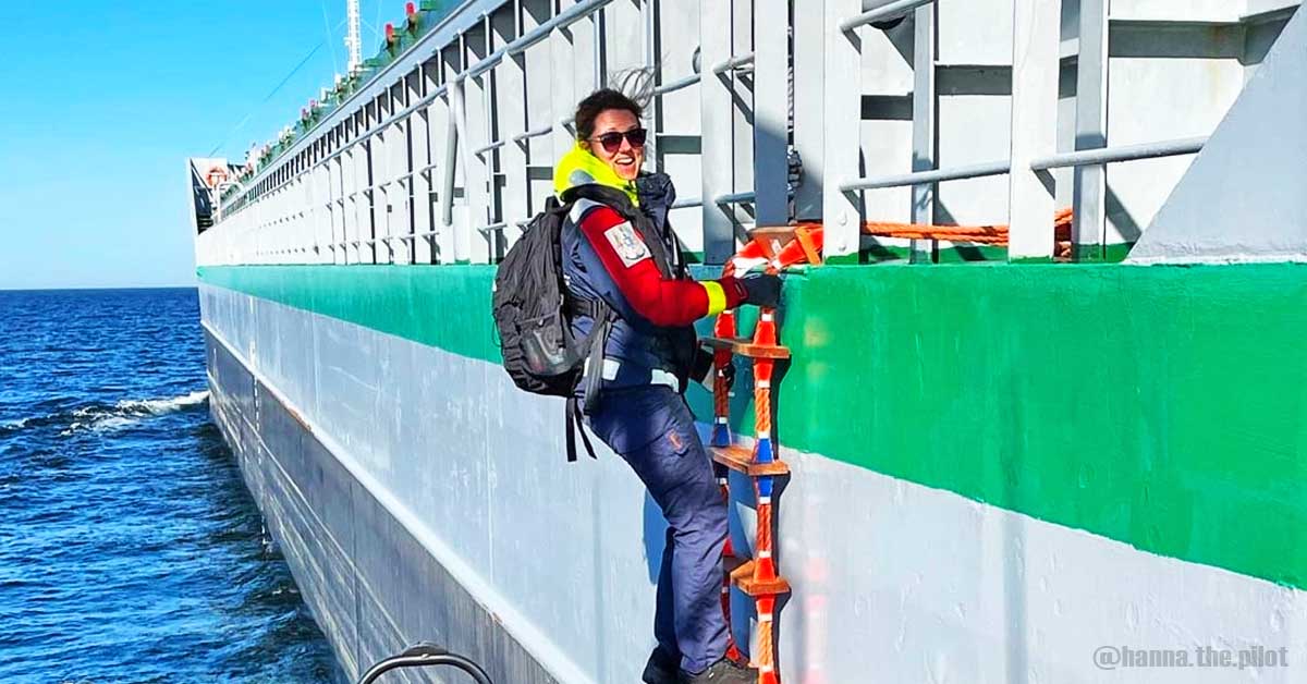 A female pilot with her backpack and wearing a lifejacket disembarks off a ship using a pilot ladder.