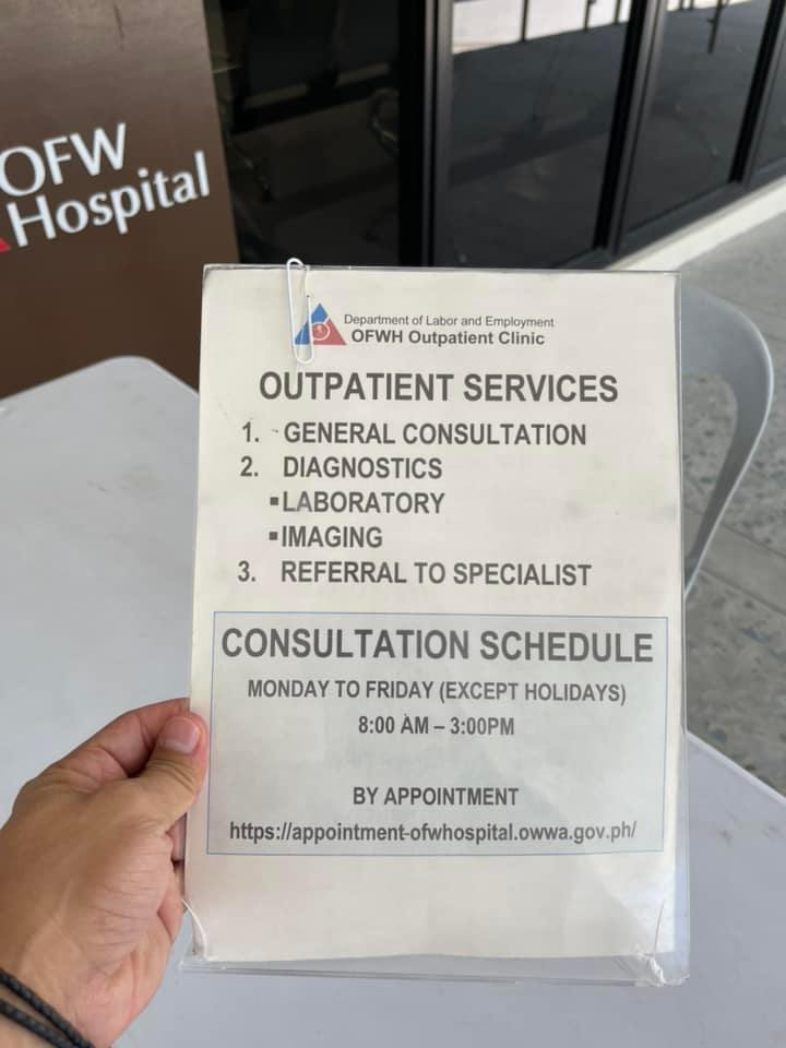 Holding a card for Outpatient Services and consultation schedule.
