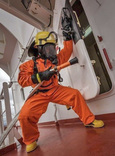 A ship's crew wearing a fireman's outfit opening a weathertight door.
