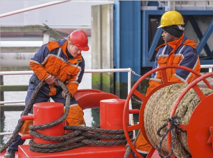 Two crew securing the loose rope aft into the bitts using the figure of eight during mooring.