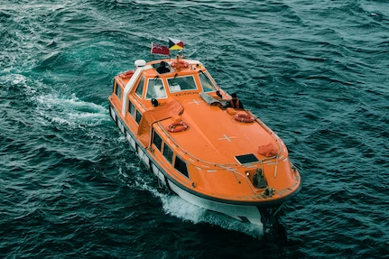 An orange lifeboat for cruise ships navigating on calm waters.
