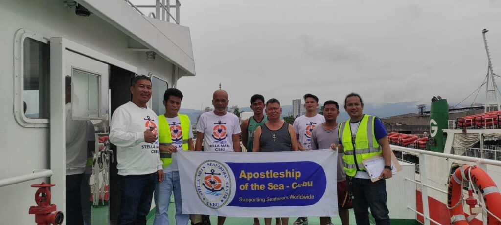 Officers from Stella Maris  Seaman's Club visit a ship docked in Cebu and together they take a picture with a banner.