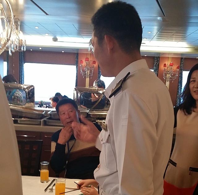 A crew in uniform talking with passengers in a cruise ship.