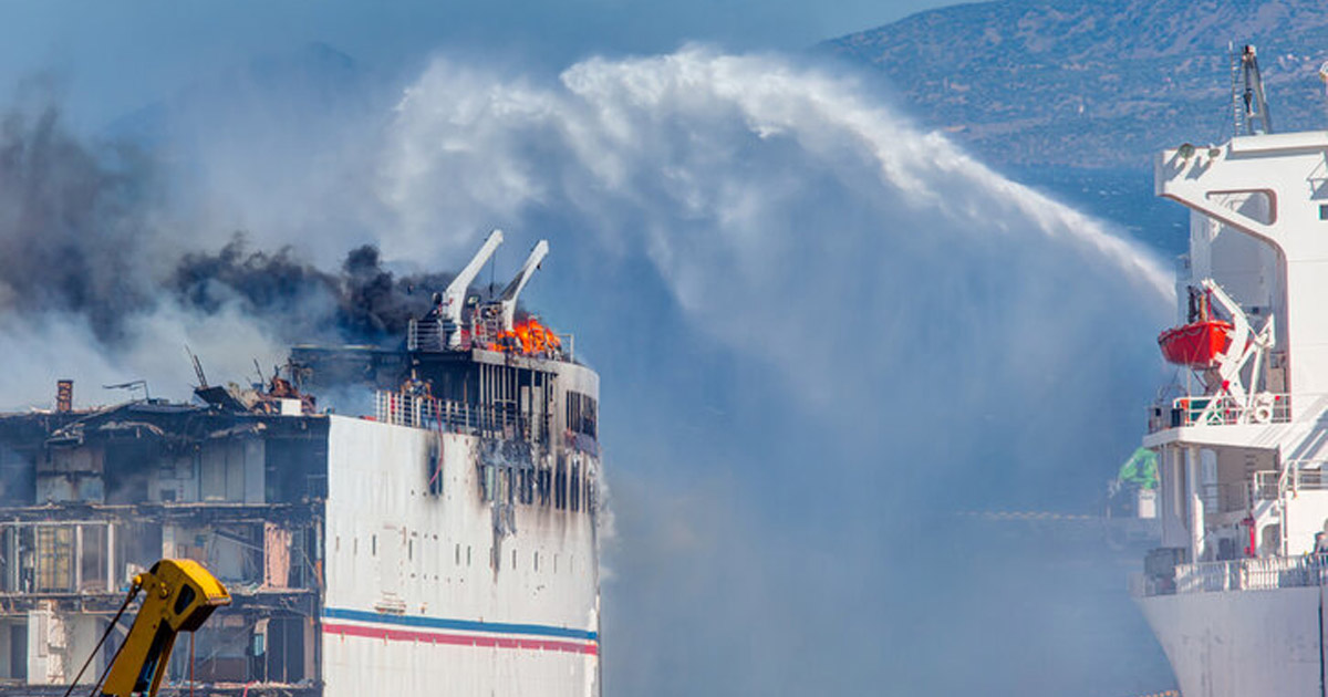 A vessel spraying water to a burning ship beside.
