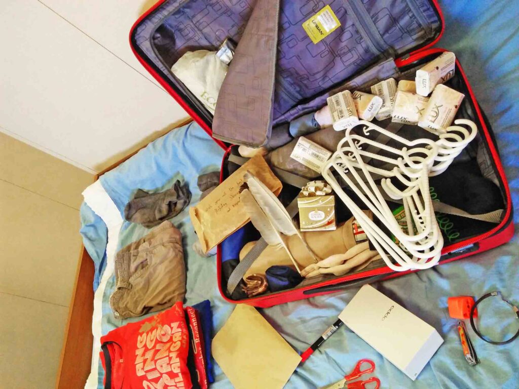 an opened luggage with folded clothes, hangers, scissors, nail cutter, dove soap, underwear, and other items packed inside a seaman's luggage.