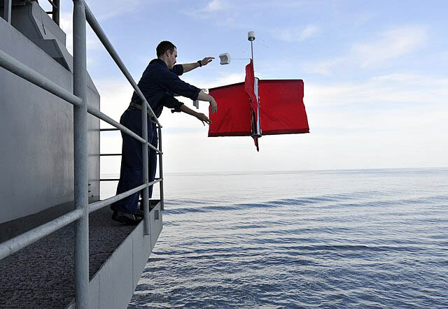 A Navy crew deploying a red Drift Buoy into the sea.