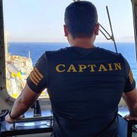 A ship captain looking out on deck from the windshield inside the ship's bridge.