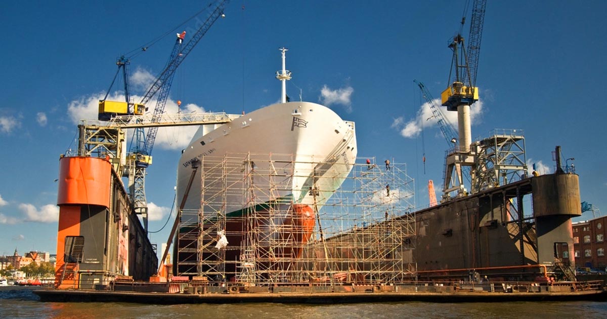 A ship in the shipyard being repaired while scaffoldings are built in front of it.