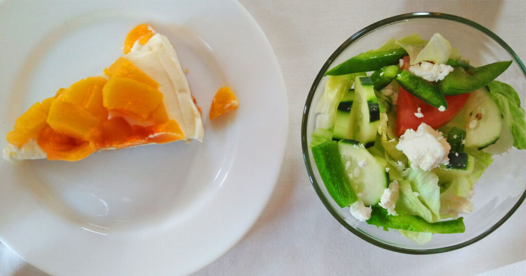 A healthy green salad in a bowl and a pie beside it.