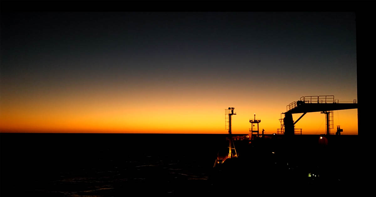 A tanker ship facing a beautiful sunset.