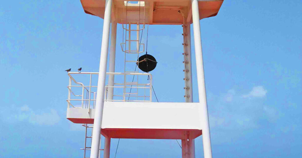 A black ball hoisted on the forward part of the ship indicating the vessel is at anchor.