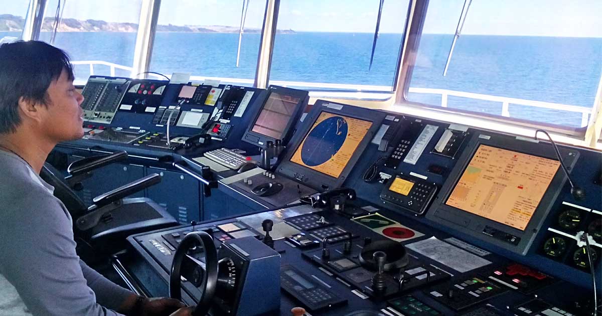 A helmsman steering the ship with various navigational tools in front of him.