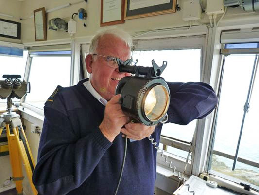 An old shipmaster using the Daylight Signaling Lamp or Aldis Lamp.