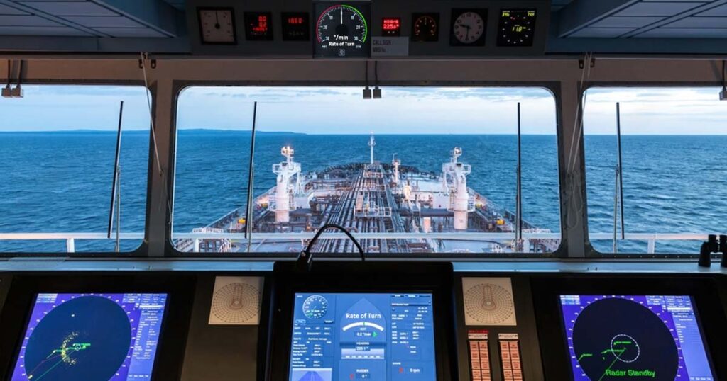 A view of the ship's deck and the sea as seen from inside the bridge with all the navigational tools including the rate of turn indicator.
